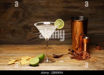 Glass of tasty margarita cocktail and nachos on wooden background Stock Photo