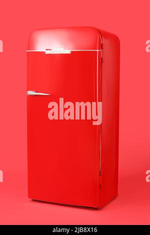 Stylish retro fridge on red background Stock Photo