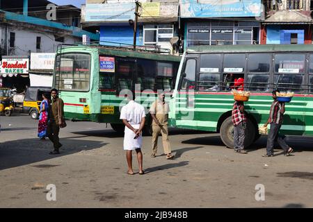 Sultan Bathery, India - January, 2017: Old green Indian buses are waiting for passengers at bus station. Men with baskets sell snack to bus passengers Stock Photo