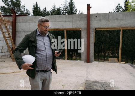 Foreman on building work on construction site. architect discussing project using smart phone construction engineers planning building. Communication Stock Photo
