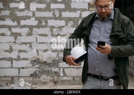 Foreman on building work on construction site. architect discussing project using smart phone construction engineers planning building. Communication Stock Photo