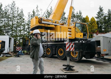 Foreman talking by phone on construction site. architect discussing project using smart phone, construction engineers planning building. Communication Stock Photo
