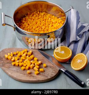 Diced pumpkin on a cutting board and in a saucepan and sliced orange. Jam making Stock Photo