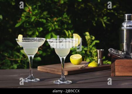 Two glasses with fresh homemade margarita cocktail on a wooden table on a patio summer evening, selective focus Stock Photo