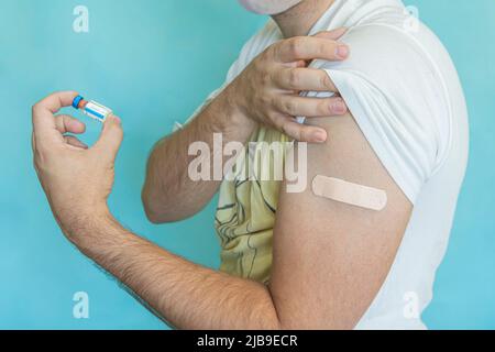 Brown adhesive bandage on young man's arm after scratch on skin or injection of vaccine. First aid. Medical, pharmacy and healthcare concept. Closeup. Stock Photo