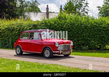 1970 70s seventies red Morris Mini Cooper 998 cc petrol small city car arriving in Worden Park Motor Village for the Leyland Festival, UK Stock Photo
