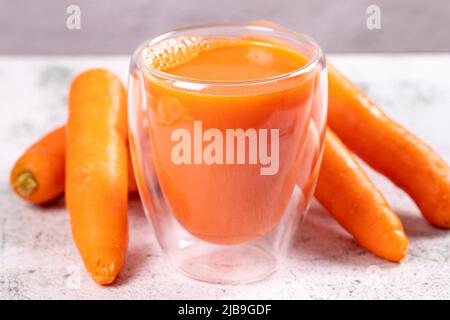 Fresh detox carrot juice in glass bottles on a gray stone