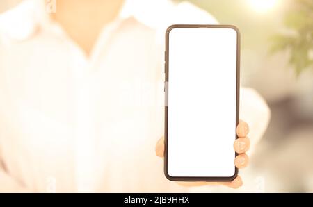 Cellphone mockup. woman in white clothes shows blank white cell phone screen. woman hand holding and showing black mobile smart phone with blank white Stock Photo
