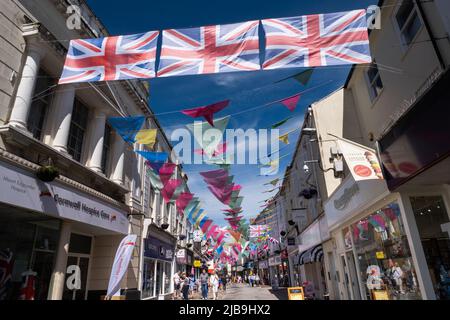 Colourful huge sized bunting and Union Flags waving in the breeze above the main shopping street of Falmouth for the Queens Platinum Jubilee weekend Stock Photo