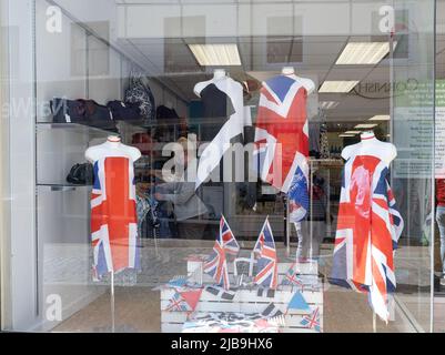 Colourful shop window display commemorating the Platinum Jubilee of Queen Elizabeth. Bright union flags draped on mannequins beside St Pirrans B&W Stock Photo