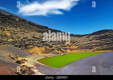 Beautiful secluded lagoon valley, red rocks, deep green lake (Lago verde), black lava sand, impressive rugged sharp steep cliffs - El Golfo, Lanzarote Stock Photo