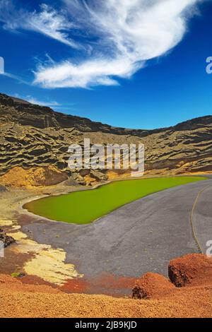 Beautiful secluded lagoon valley, red rocks, deep green lake (Lago verde), black lava sand, impressive rugged sharp steep cliffs - El Golfo, Lanzarote Stock Photo