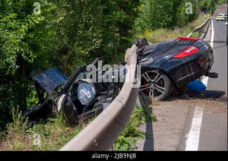 Polich, Germany. 04th June, 2022. 04 June 2022, Rhineland-Palatinate, Pölich: A sports car is trapped after an accident under a guardrail on the B53 federal highway between Mehring and Pölich. One person was slightly injured in the accident, a 53-year-old from Trier died. The driver of the accident is on the run, according to the Trier police department. The police are looking for witnesses. Photo: Harald Tittel/dpa Credit: dpa picture alliance/Alamy Live News Stock Photo