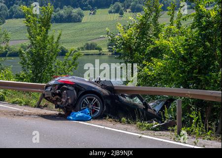 Polich, Germany. 04th June, 2022. 04 June 2022, Rhineland-Palatinate, Pölich: A sports car is trapped after an accident under a guardrail on the B53 federal highway between Mehring and Pölich. One person was slightly injured in the accident, a 53-year-old from Trier died. The driver of the accident is on the run, according to the Trier police department. The police are looking for witnesses. Photo: Harald Tittel/dpa Credit: dpa picture alliance/Alamy Live News Stock Photo