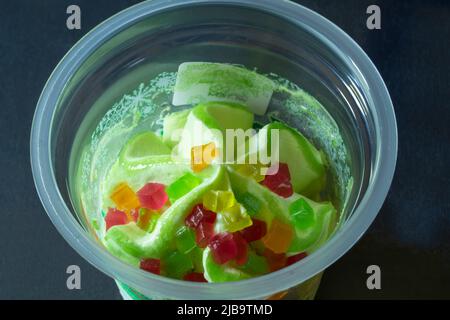 Sweet ice cream in a plastic cup on the table. Food on a dark background Stock Photo