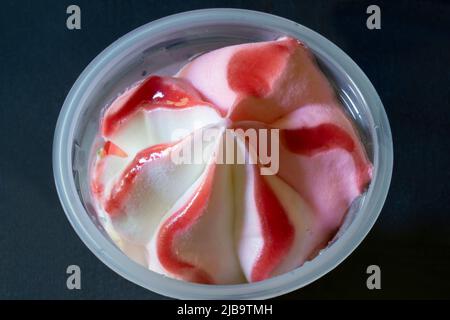 Sweet ice cream in a plastic cup on the table. Food on a dark background Stock Photo