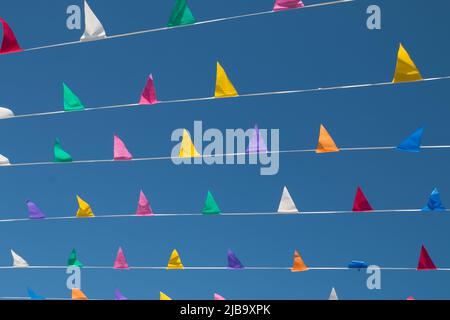 Multicolored, triangular flags against the background of a blue, cloudless sky. Stock Photo