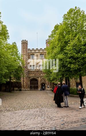 Student wearing a gown and red stole on Graduation Day at the main entrance of Trinity College, the Great Gate, Cambridge, Cambridgeshire, England, UK Stock Photo