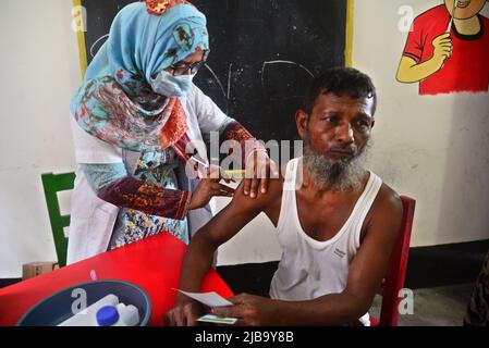 Slum dweller receives a Booster Dose of COVID-19 vaccine at a makeshift vaccination center during a national campaign at Karail Slum in Dhaka, Bangladesh, on June 4, 2022 Stock Photo