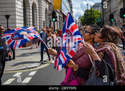 A mother and daughter holding Union Flags stop for a selfie as they celebrate the Queen's Platinum Jubilee in London on 2 June 2022. Stock Photo