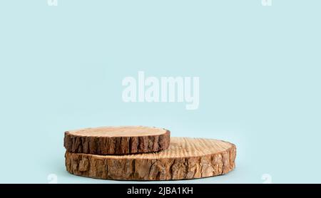 Two pine tree wood discs stacked as a podium for products, blue color background with lot of copy space, studio shot. Stock Photo