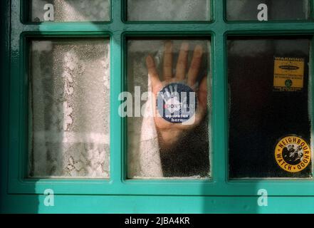 Neighbourhood Watch sticker on a window with a hand against the window Stock Photo