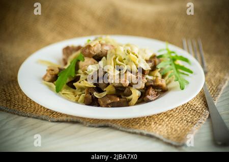 Homemade boiled noodles with meat and eggplant in a plate on a wooden table Stock Photo