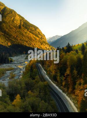 Mountain road going into the distance next to the river Stock Photo