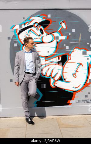 Ipswich Suffolk UK May 27 2022: A handsome businessman in a grey suit in front of some urban artwork