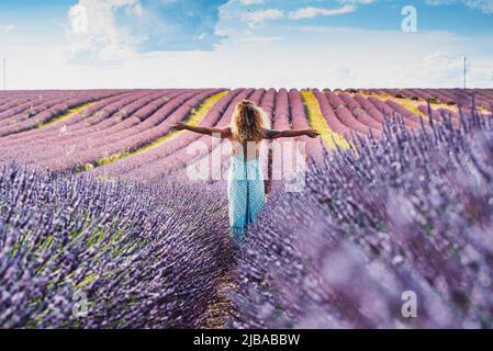 Happy and free traveler woman outstretching arms and enjoy amazing nature landscape in the middle of a violet lavender field flowers scenic destinatio Stock Photo