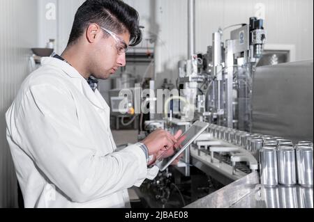 Factory worker inspecting production line on beverage factory with computer tablet. High quality photo Stock Photo