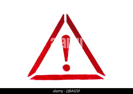 Exclamation mark in triangle drawn by red paint on white wall. Warning sign to prevent potential problems traffic accident. Close-up. Stock Photo