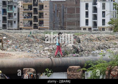 Delhi, Delhi, India. 4th June, 2022. A boy walks on a pipeline near a dump full of garbage at Taimoor Nagar on the eve of World Environment Day in New Delhi. (Credit Image: © Kabir Jhangiani/Pacific Press via ZUMA Press Wire) Stock Photo