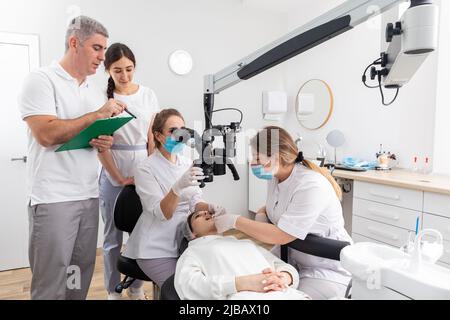 Group of students in dental clinic learn watching dental treatment with a microscope Stock Photo