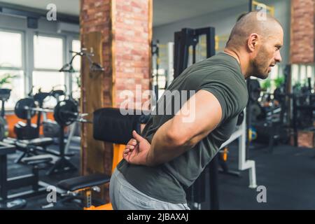 Muscular man having a back pain , view from a side, sport concept. High quality photo Stock Photo