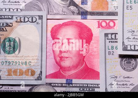 A one hundred RMB Yuan currency note from China centered in a bordered concept by a number of one hundred dollar notes from the United States. Stock Photo