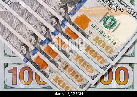 A number of one hundred dollar bills arranged in a repeating pattern to show the anti-counterfeiting color shifting printing ink technology on front. Stock Photo