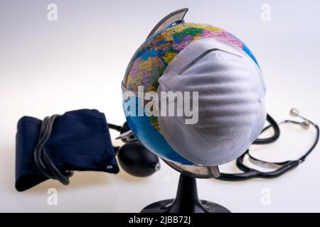 Protective surgical face mask on a terrestrial globe model. Coronavirus Concept. Surgical mask with rubber ear straps. Corona virus,  nCoV, covid 19. Stock Photo