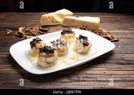 Homemade rondelli with four cheese and mushuroom sauce in white plate on rustic white wooden table background, soft light Stock Photo