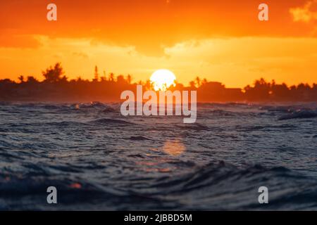 Sunset over the ocean. sun sets behind the trees on the horizon. Beautiful sunset in the Indian ocean. Evening seascape in the tropics. Stock Photo