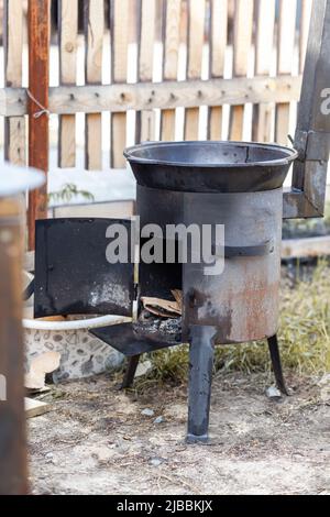 Cooking food or pilaf in a cauldron on fire. Cooking in cauldron on open fire in nature. Bowler on bonfire in forest. Close-up fire flame. Copy space. Stock Photo