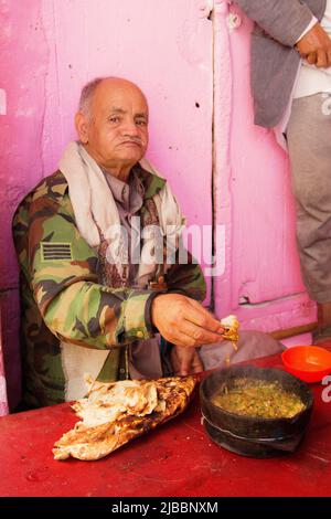 old man eating Yemeni traditional food in the old city of Sana'a - Yemen Stock Photo