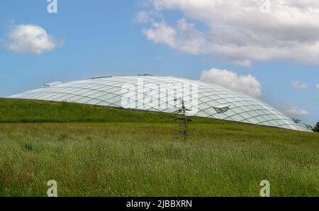 Futuristic conservatory dome of glass panels in steel joists, set into a hillside. Wales Botanic Garden world's largest single span glasshouse Stock Photo