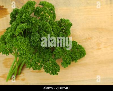 Bunch of curly parsley on a wooden background. Fresh green parsley top view. Sprigs of curly parsley close-up. Stock Photo