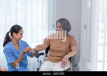 Young nurse taking care elderly disabled woman sitting in wheelchair with copy space. A female supporter assisting a senior patient while she smiling Stock Photo