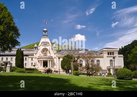 Casino building in Sinaia on a sunny Spring day and people relaxing in the green park. Sinaia, Romania - May 15, 2022 Stock Photo