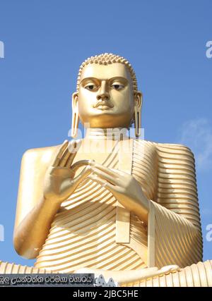 5th century golden Buddha sits above the Golden Temple at Sigiriya, Dambulla, near the Dambulla Temple Complex in Sri Lanka. The posture is Dharma Cha Stock Photo