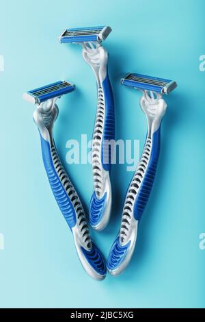 Three shaving machines on a blue background with free space, top view Stock Photo