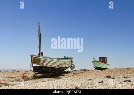 On the expansive shingle beach of Dungeness Headland in Kent are several old, weathered fishing boats, many abandoned. Stock Photo