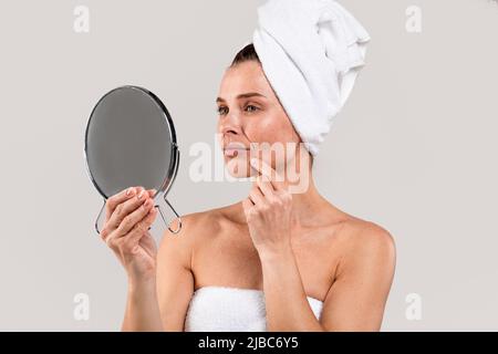 Skin Problems. Unhappy Middle Aged Female Looking At Magnifying Mirror Stock Photo